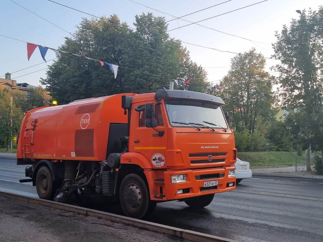 Три вакуумные пылеуборочные машины днем работают на улицах города.